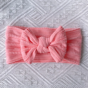 Detail of pink knitted baby headband with large bow and soft ribbed texture on fabric