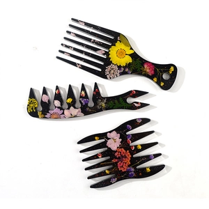 Detail of three black resin hair picks with colorful dried flowers and gold glitter flakes