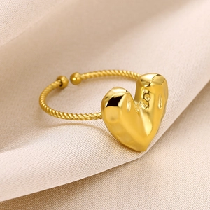 Macro view of adjustable gold heart ring with twisted rope band on beige silk fabric