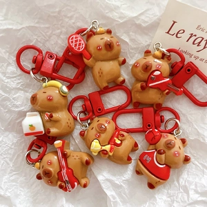 Macro shot of assorted cute capybara keychains with vibrant red clips on white fabric