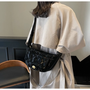 Close-up of black quilted dumpling bag with glossy finish and golden twist lock detail