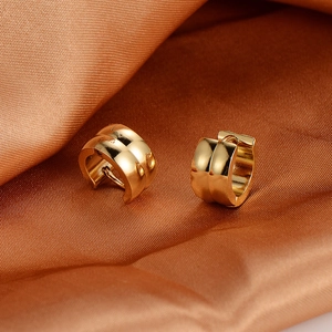 Polished gold stainless steel wide hoop earrings set on elegant orange silk fabric