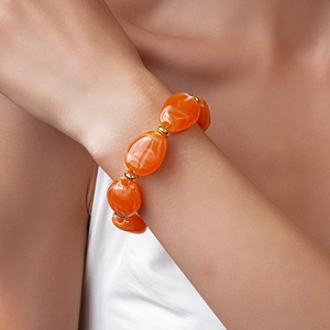 Detail of chunky orange acrylic oval beads and golden spacers on a stylish wrist bracelet