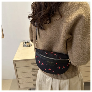 Detail of a black crossbody bag with cherry print worn by a model in a lifestyle setting