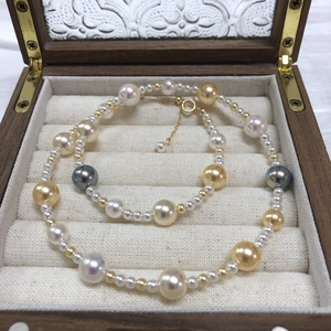 Detail of multi-color pearl necklace with gold clasp inside a vintage wooden jewelry box