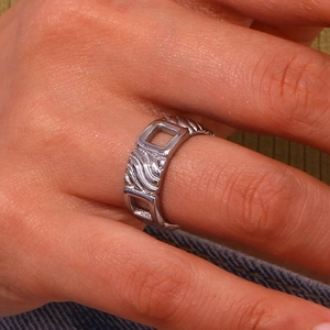 Detail of silver hollow square ring with wavy texture worn on a finger