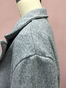 Détail du manteau gris texturé avec col à revers et coutures aux épaules précises