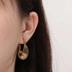 Vue détaillée d'un modèle portant une boucle d'oreille spirale dorée de style moderne