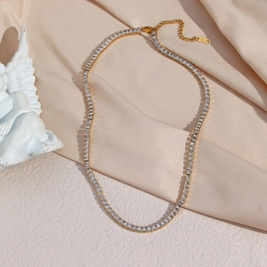 Gros plan du collier plaqué or avec zircons carrés sur soie rose et gravure 18K