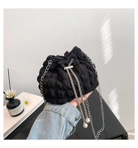 Detail of black pleated bucket bag with silver chain strap and pearl pendant