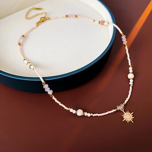 Detail view of 18K gold plated sunflower pendant necklace with pink stones and beads