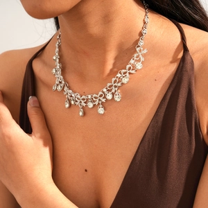 Detailed view of luxury silver bow necklace with crystal teardrop pendant on model neck
