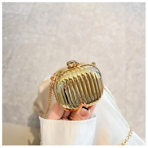 Close-up of golden metallic mini evening bag with pleated texture and gold chain strap
