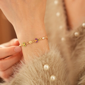 Gros plan d'un bracelet vintage en or avec breloques en émail coloré sur manche