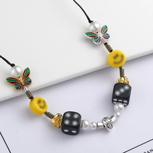 Macro detail of multi-element beaded necklace with skull, butterfly, and dice pendants