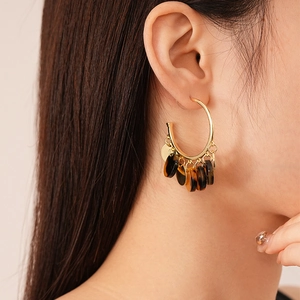 Close-up of C-shaped golden earrings with vintage leopard resin discs on female model