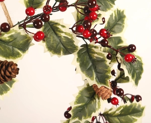 Macro detail of Christmas holly branch with red berries and pine cones on warm background