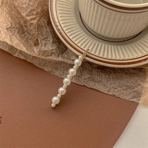 Detail of elegant pearl hair clip with gold metal base on vintage brown background