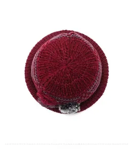 Detailed top view of wine red winter knit hat with floral ornament and faux fur pompom