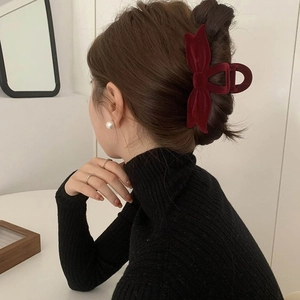 Elegant red velvet bow hair claw clip styled on dark hair from a side back view