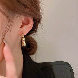 Detail of gold beaded drop earrings with five gradient spheres on a female model