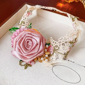 Detail of pink satin rose necklace with pearls and lace in a wooden jewelry box