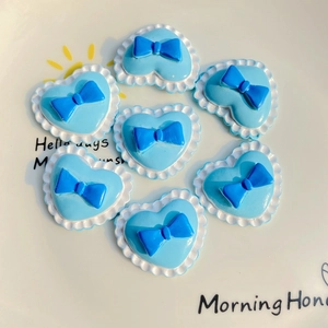 Blue heart-shaped DIY resin charms with dark blue bow details and white wavy edges