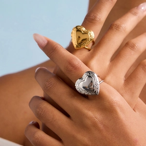 Detail of vintage heart locket ring with ornate floral engraving in gold and silver