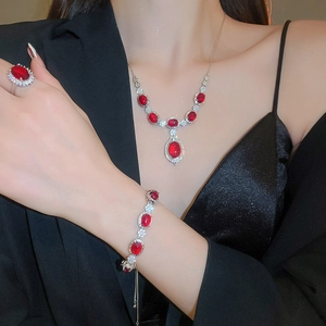 Close-up of elegant floral silver jewelry set with ruby red stones and cubic zirconia