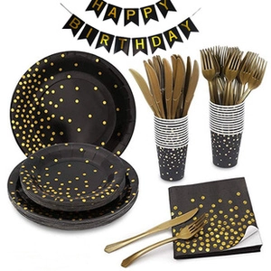 Macro shot of black party tableware set with gold foil dots including plates and cups