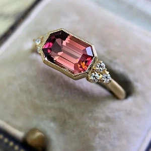 Vintage gold engagement ring with emerald cut red gemstone and small white diamonds