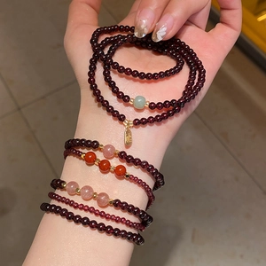 Close-up of double-layered garnet and strawberry quartz bracelet with gold Fu charm