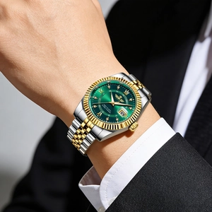 Detail of luxury men's steel watch with green dial and gold calendar window on wrist