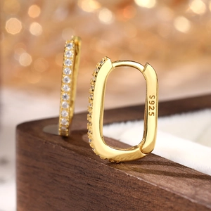 Detailed close-up of 925 sterling silver gold-plated oval hoop earrings with white zircon