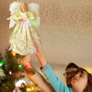Close-up of lighted angel tree topper with gold glitter skirt and soft feather wings