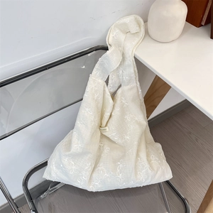 Detailed view of cream-white tote bag with floral 3D embroidery and textured fabric