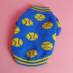 Detailed view of blue knitted pet sweater with yellow tennis patterns on pink backdrop