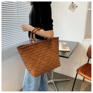 Detail of hand-woven brown tote bag featuring natural bamboo handles and textured design