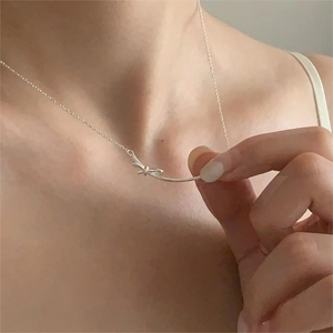 Close-up of a minimalist 925 sterling silver bow knot necklace on female model neck