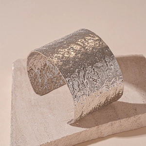 Close-up of silver wide cuff bracelet with textured hammered metal finish on stone