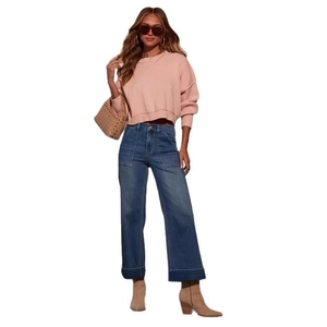 Close-up of high-waisted wide-leg denim jeans styled with a pink sweater and accessories