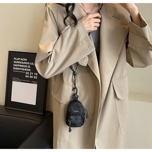 Girl wearing a black nylon mini crossbody bag with a woven lanyard and fashion label