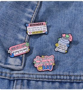 Close-up of four colorful enamel lapel pins with mental health quotes on denim fabric