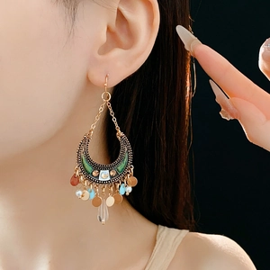 Macro shot of bohemian crescent earrings with green enamel and crystal waterdrop fringe