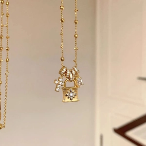 Close-up of golden bead chain necklace with zircon padlock and cross pendants