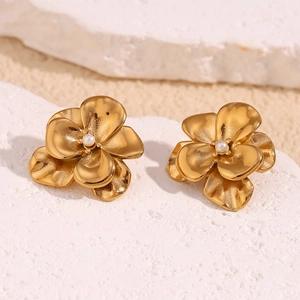 Macro detail of vintage gold-plated petal earrings with elegant white pearl center