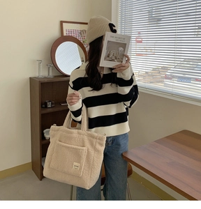 Chic cream fleece tote bag styled with a striped sweater and casual lifestyle items