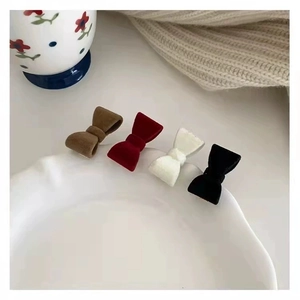 Sweet velvet bow hair clips in coffee, wine red, cream, and black on a ceramic plate