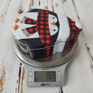 Detailed weight measurement of a cute penguin-shaped Christmas tin box at 86.9g
