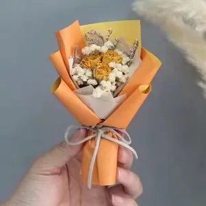 Close-up of mini dried yellow rose bouquet with white baby's breath in hand